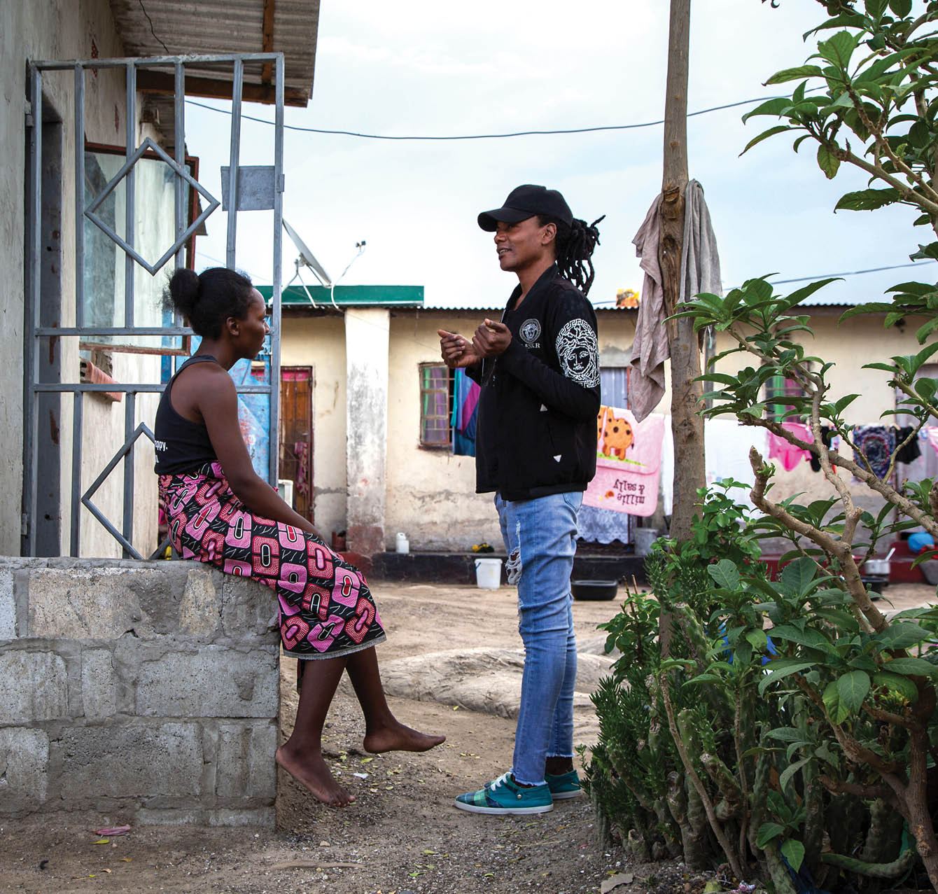 Jomell M’hango, a 28 year old DZL client, chats with his friend and neighbour, Mable, outside his house in John Laing Compound, Lusaka Zambia on 25 November 2020. Frontline AIDS, in partnership with the Elton John AIDS Foundation, has created a COVID-19 Emergency Fund, which enables healthcare workers from Dignitate Zambia’s (DZL), a Zambia-based community organisation, to offer mobile outreach care support to communities most affected by HIV. The mobile support entails HIV testing, food and grocery supplies, and counselling support for those struggling with the lockdown restrictions as well as survivors of gender-based and domestic violence.