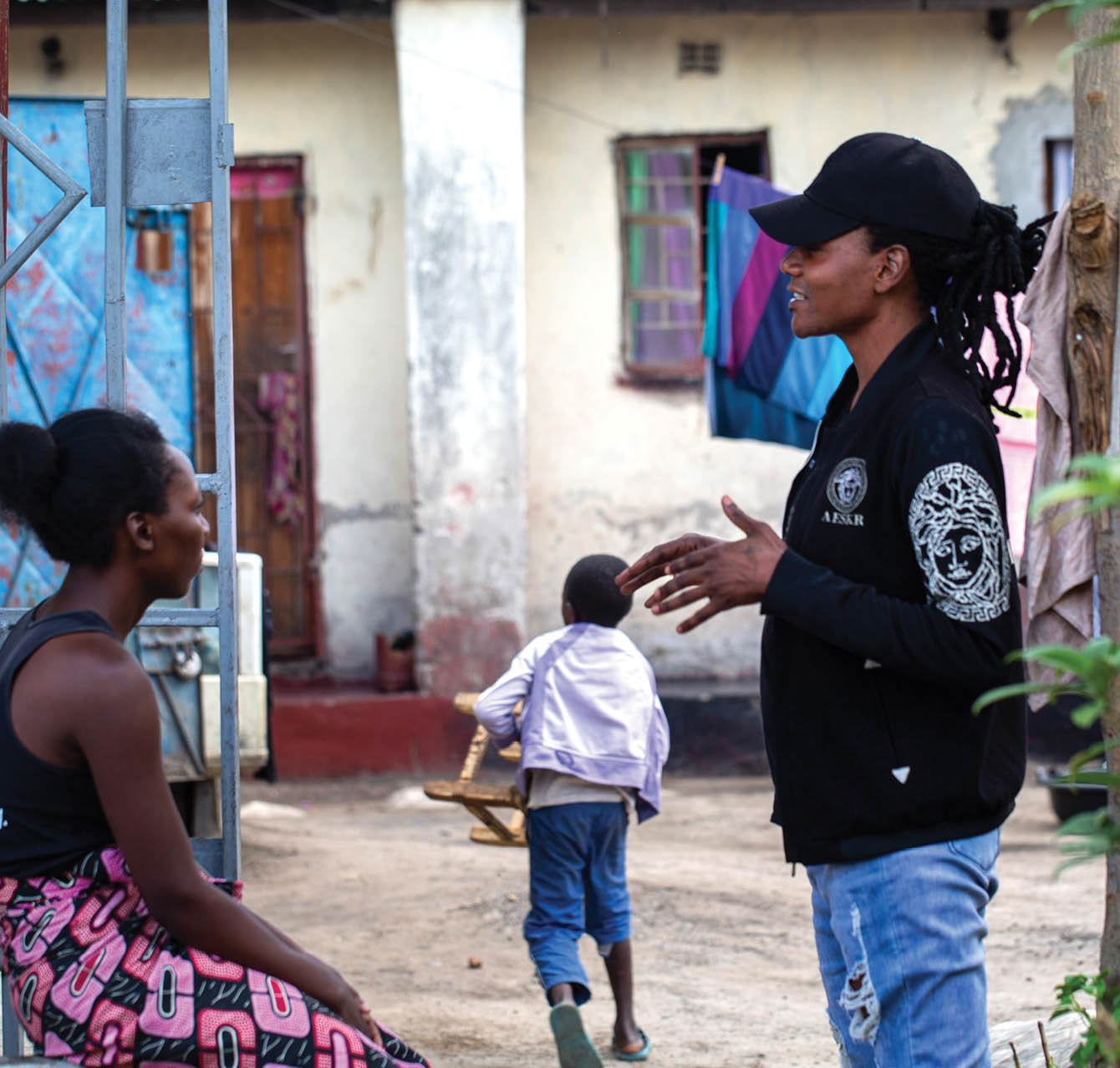 Jomell M’hango, a 28 year old DZL client, chats with his friend and neighbour, Mable, outside his house in John Laing Compound, Lusaka Zambia on 25 November 2020. Frontline AIDS, in partnership with the Elton John AIDS Foundation, has created a COVID-19 Emergency Fund, which enables healthcare workers from Dignitate Zambia’s (DZL), a Zambia-based community organisation, to offer mobile outreach care support to communities most affected by HIV. The mobile support entails HIV testing, food and grocery supplies, and counselling support for those struggling with the lockdown restrictions as well as survivors of gender-based and domestic violence.
