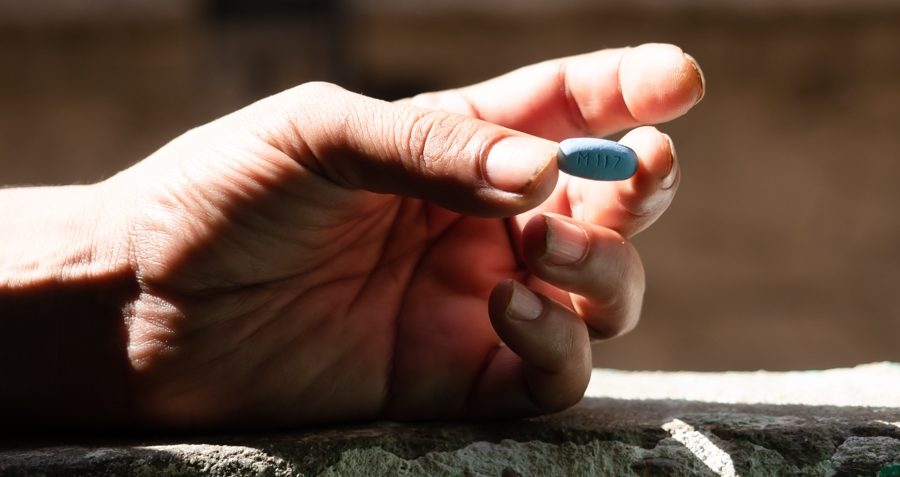 A close up of a person's hand holding a blue pill