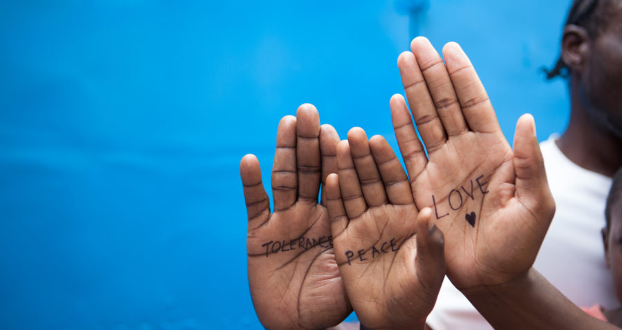Three hands with the words tolerance, peace and love written on them