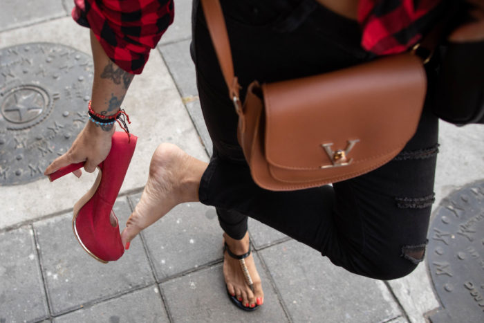 A transgender woman takes off her sandals and puts on some red stilettoes