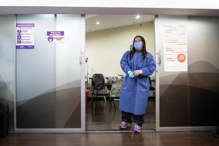 A transgender woman in PPE stands in a COVID testing clinic