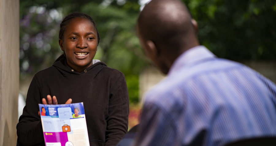 A young woman shows a young man a leaflet on SRHR.