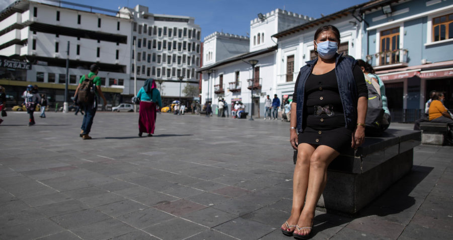 A woman wearing a face mask and sitting in a town square