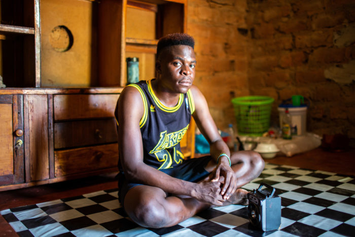 A young man sits on the floor of his kitchen