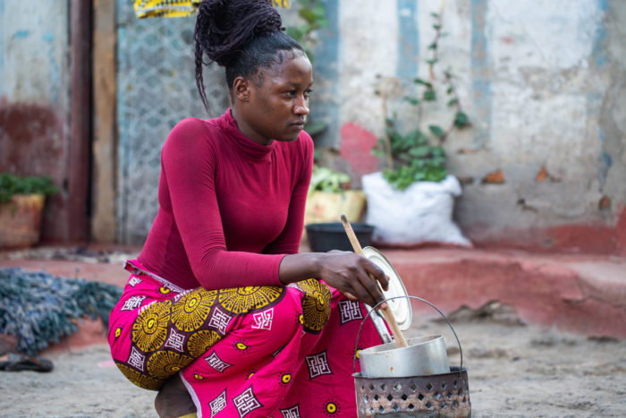 A young woman stirs a pot of food