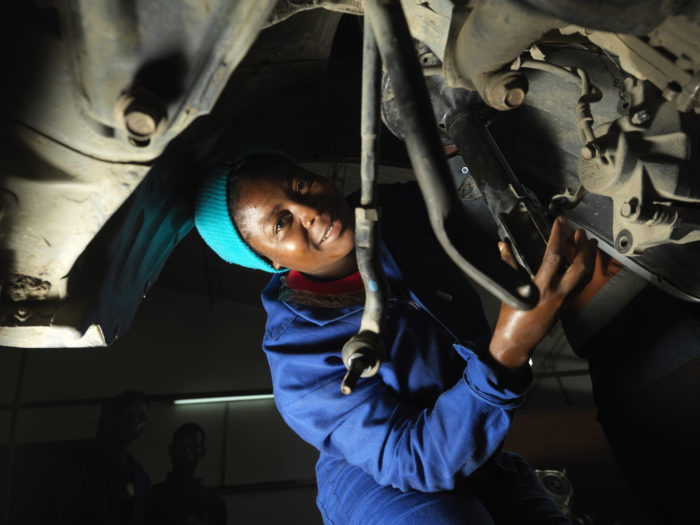 Young woman fixing a car