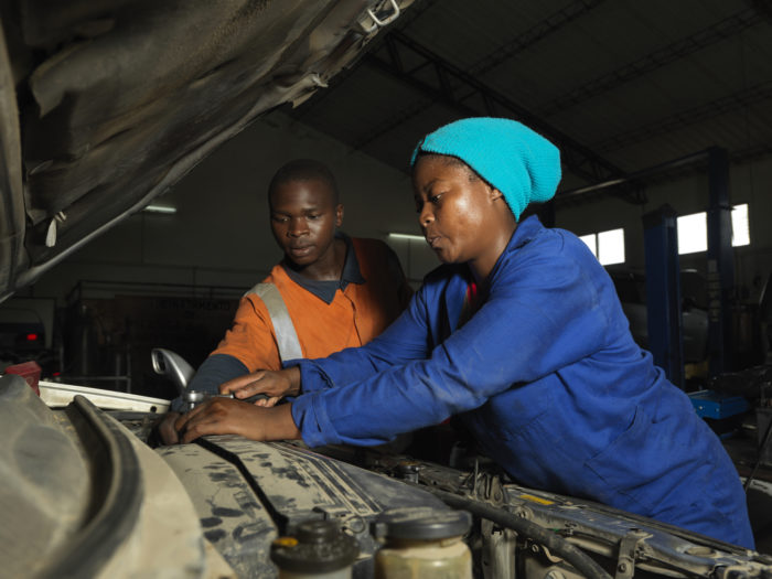A young man and woman work on fixing a vehicle