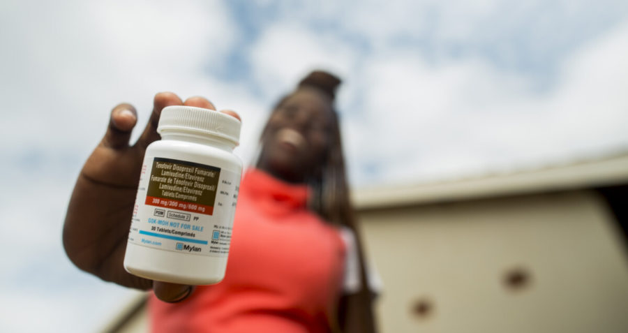 A young woman holds a bottle of HIV treatment pills