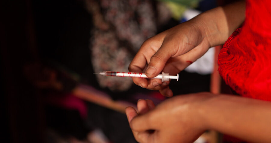 A woman holds a needle and syringe