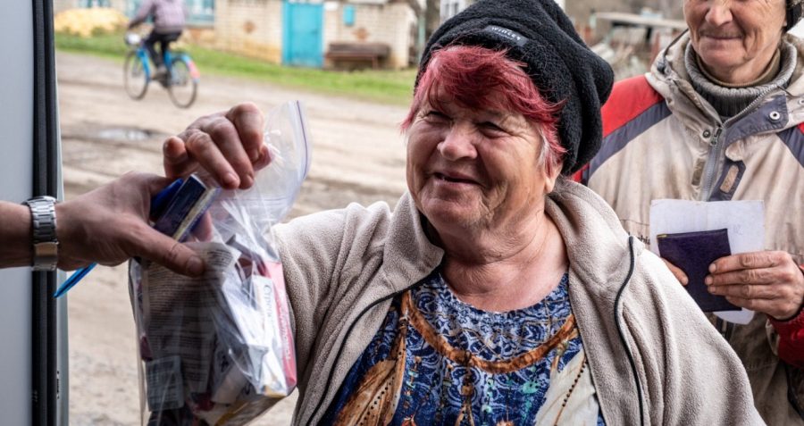 A woman stands holding a bag with medicines in front of a mobile van in Ukraine.