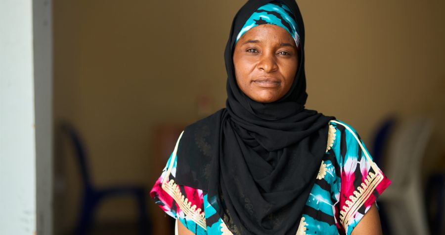 A woman wearing a black hijab sits on a chair facing forward