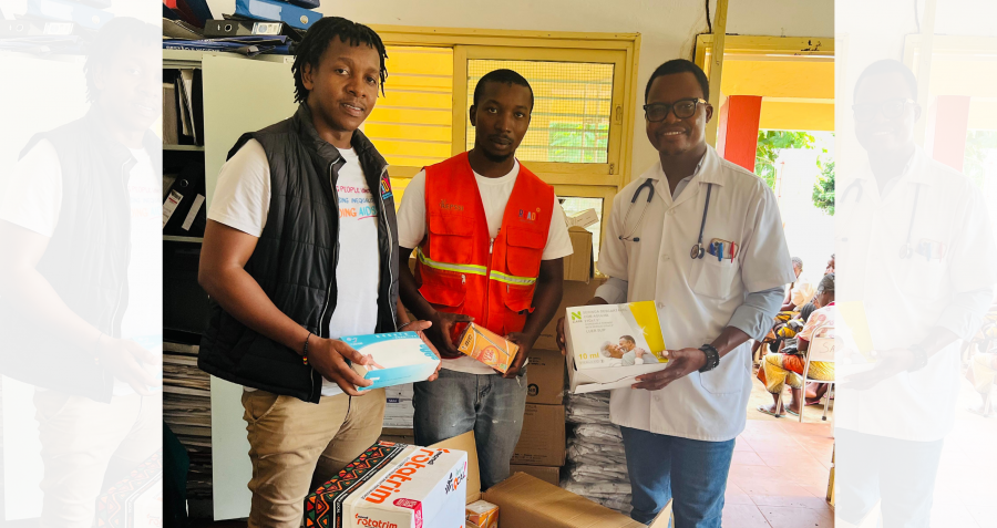 Three men stand in a building holding emergency supplies
