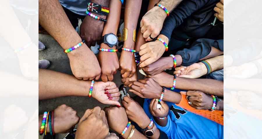 A circle of hands with coloured bracelets