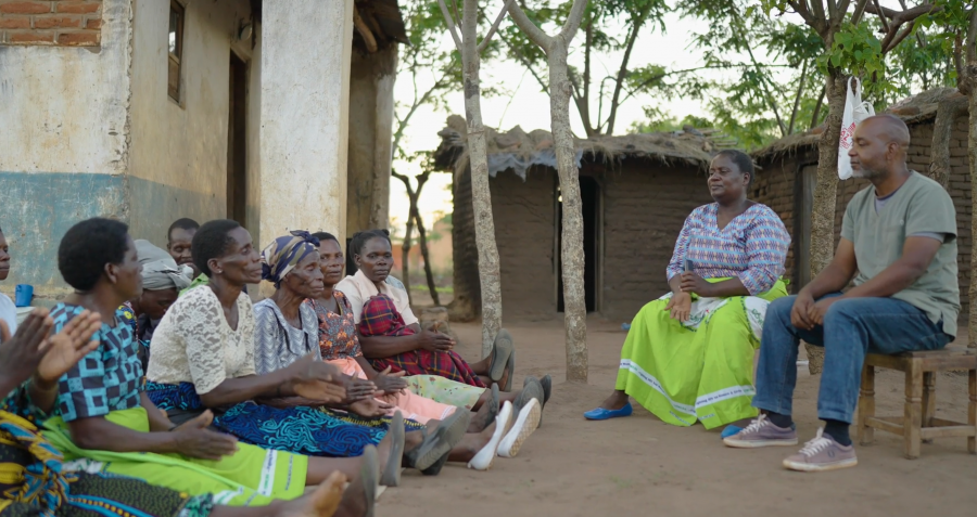 A group of people sit together outside a building